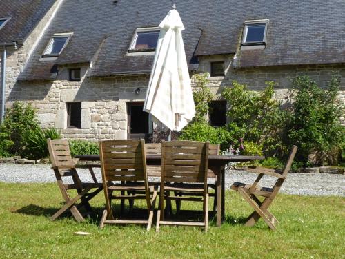 a table and chairs with an umbrella on the grass at FORET TOTEM - Hébergements nature et bien-être en pleine forêt in Persquen
