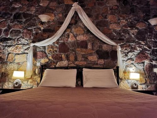 a bedroom with a bed with a stone wall at Ataviros Hotel in Émbonas