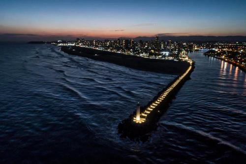 a long pier with lights in the water at night at Pousada Azimute in Torres