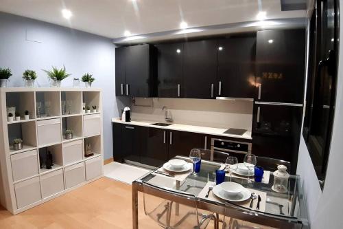 a kitchen with a glass table and black cabinets at LUXEinBurgos Atico con Vistas Espectaculares in Burgos