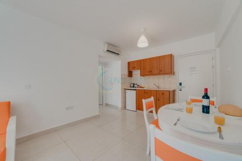 a white kitchen with a table and chairs and a counter top at Christos Napa Self Serviced Apartments in Ayia Napa