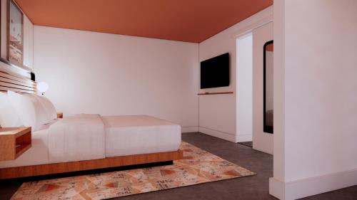 a white bedroom with a bed and a television at The Myriad Hotel Louisville, Tapestry Collection by Hilton in Louisville