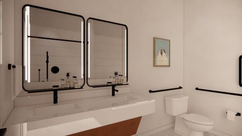 a bathroom with a sink and a toilet and a mirror at The Myriad Hotel Louisville, Tapestry Collection by Hilton in Louisville