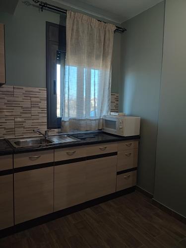 a kitchen with a microwave and a sink and a window at Aithra Studio in Tripolis