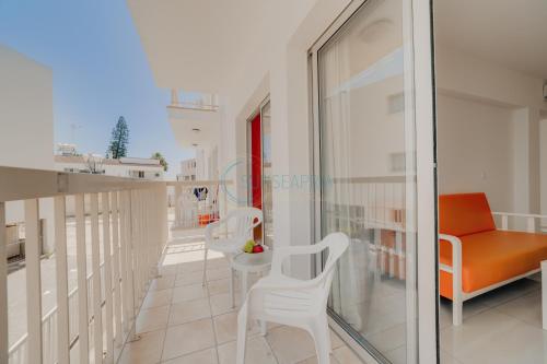 a balcony with an orange chair and a couch at Christos Napa Apartments in Ayia Napa