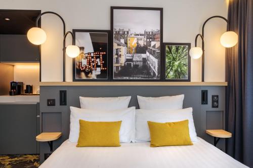 a bedroom with a bed with two yellow pillows at Best Western M-Treize Paris Asnieres in Asnières-sur-Seine