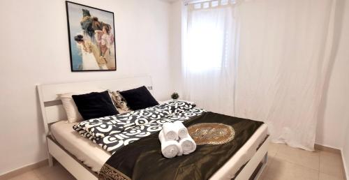 a white bed with black and white sheets and white shoes at Large apartment with sea view in Bat Yam