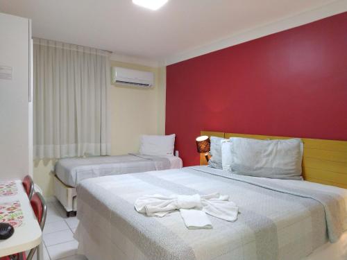 1 dormitorio con 2 camas y pared roja en Ponta Negra Beach beira-mar ap 216, en Natal