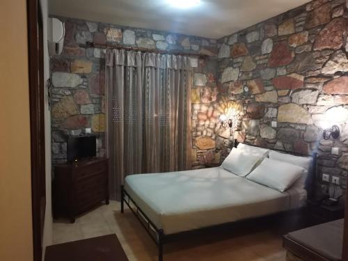 a bedroom with a bed and a stone wall at Ataviros Hotel in Émbonas