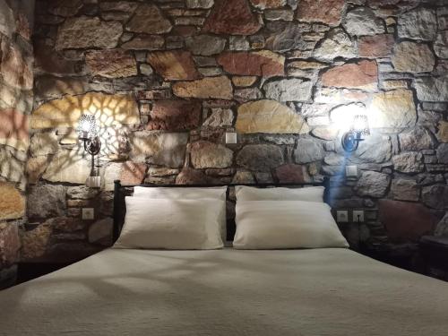 a bedroom with a stone wall with a bed and lights at Ataviros Hotel in Émbonas
