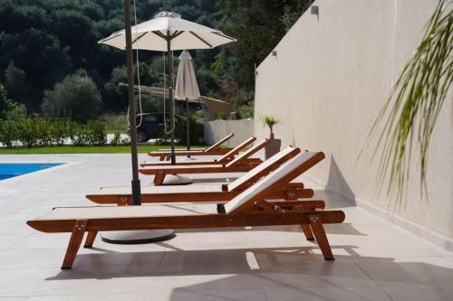 a row of lounge chairs with an umbrella at MERAVIGLIA in Parga