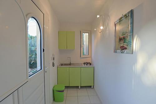 małą kuchnię z zielonymi szafkami i zlewem w obiekcie Villa del Sole w mieście Torre Suda