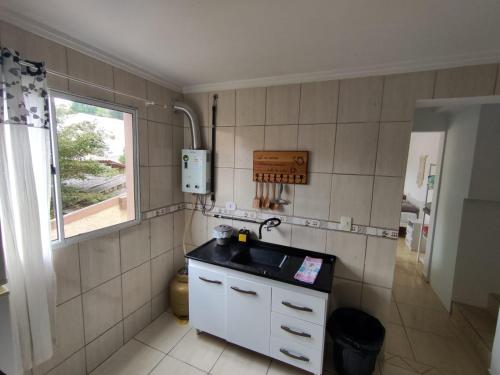 uma pequena cozinha com um lavatório e uma janela em Mountain View em Curitiba
