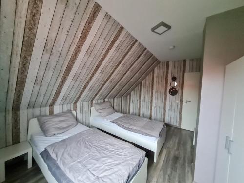 two beds in a small room with wooden walls at Ferienwohnung Schmidt in Waabs