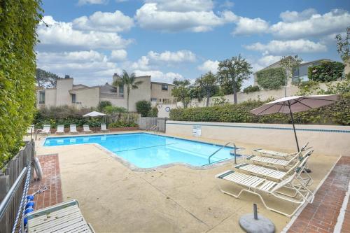 a swimming pool with chairs and an umbrella at Oceanfront Fully Remodeled 2BR 2BA, Pool, Hot Tub, Gated Parking in Solana Beach