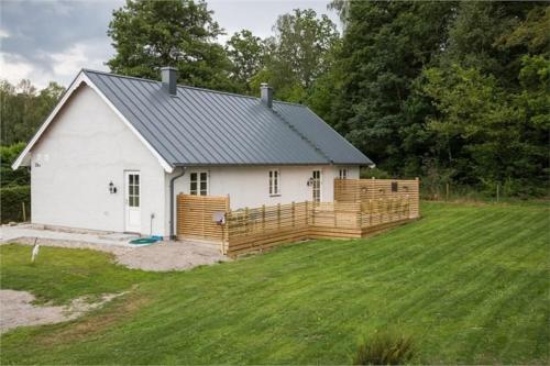 una casa blanca con una valla de madera en un patio en Beautiful and cosy house near the lake en Olofström