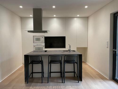 a kitchen with a black island with two bar stools at Casa Fermar in Esposende
