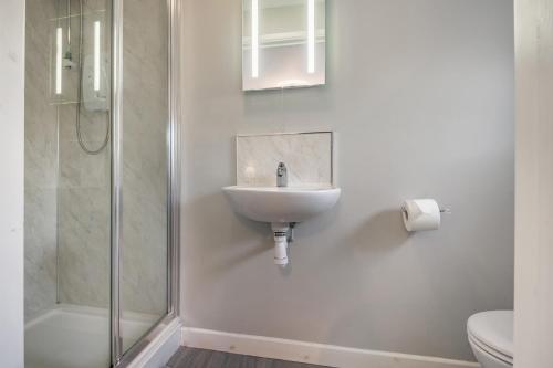 a white bathroom with a sink and a shower at Sunny Cottage in Brecon