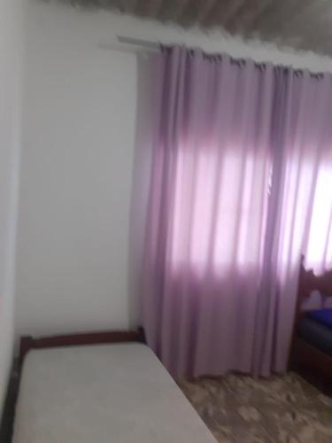 a bedroom with a bed and a purple curtain at CASA PRAIA GRANDE i146 in Praia Grande