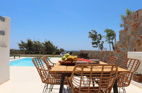 una mesa y sillas con un bol de fruta. en The Nine Graces - Kastraki Villas with Private Swimming Pool, en Kastraki Naxou