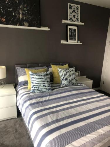 a bed with striped sheets and pillows in a bedroom at Luxury apartment stunning views in Manchester