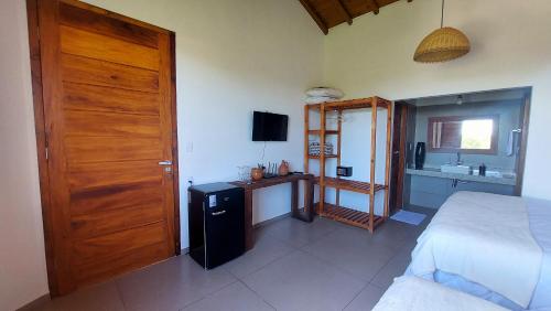 sypialnia z łóżkiem i drewnianymi drzwiami w obiekcie Aldeia Biribiri - Pousada w mieście Caraíva