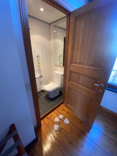a bathroom with a toilet and a wooden door at Artist's Loft & Garden in Ghent