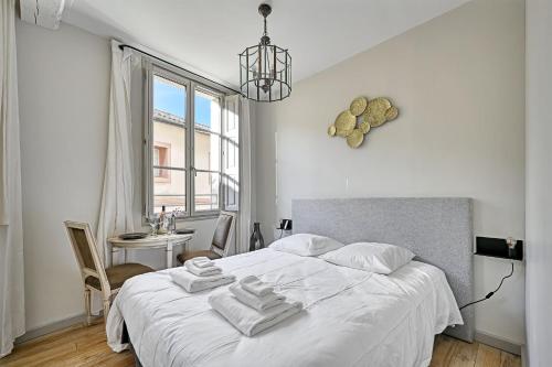 biała sypialnia z łóżkiem i ręcznikami w obiekcie Au cœur des Papes, dans bâtisse de charme studios & appartements en cœur de ville w Awinionie