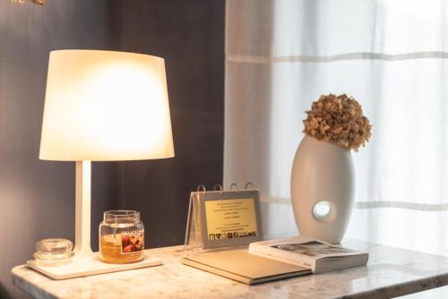 a table with a lamp and a book and a vase at Hotel Suite Inn in Udine