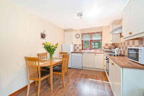 una cocina con mesa y sillas y una cocina con armarios blancos. en ASH 2 Bedroom Lodge, en Kingsnorth