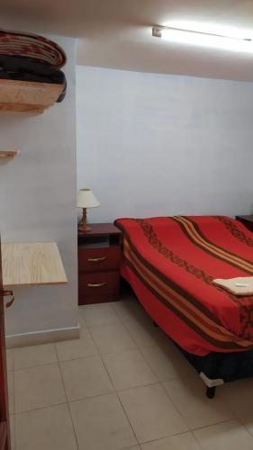 um quarto com uma cama com um cobertor vermelho e uma mesa em Virgen de Copacabana em Purmamarca