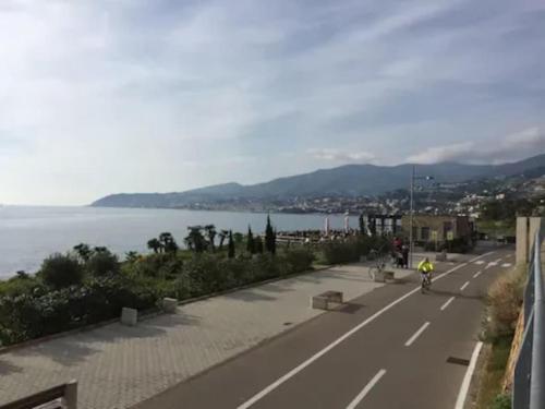 a person riding a bike down a road next to the water at Casa Sveva, a pochi passi dalle spiagge e dal centro di Arma di Taggia. in Arma di Taggia