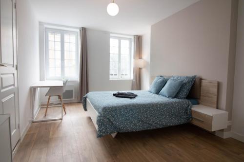 een slaapkamer met een bed, een bureau en 2 ramen bij Home2Stay Valognes in Valognes