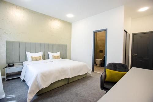a bedroom with a large white bed and a chair at Benefice Hotel Yerevan-通緝 in Yerevan