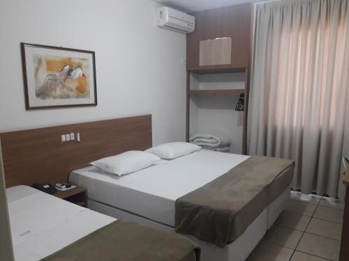Habitación de hotel con 2 camas y ventana en Hotel Vivendas Centro, en Erechim