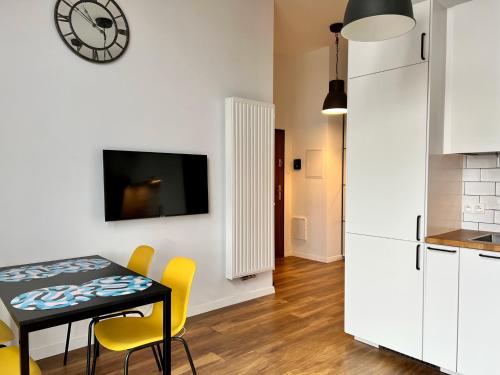 a kitchen and dining room with a table and yellow chairs at Loft Premium Apartments in Łódź