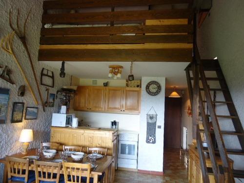 une cuisine avec une table et des chaises ainsi qu'un escalier dans l'établissement Duplex à La Clusaz avec cheminée et balcon, 2 ch, parking - FR-1-459-12, à La Clusaz