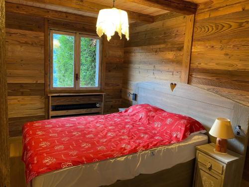 - une chambre avec un lit rouge dans une cabane en bois dans l'établissement Charmant 3 pièces rénové avec terrasse, proche des pistes - La Clusaz, Le Crêt du Merle - FR-1-459-28, à La Clusaz