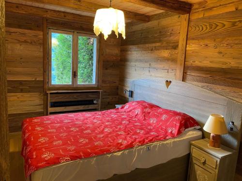 a bedroom with a red bed in a wooden cabin at Appartement La Clusaz, 3 pièces, 6 personnes - FR-1-459-28 in La Clusaz