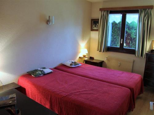 - une chambre avec un lit doté d'un couvre-lit rouge et d'une fenêtre dans l'établissement Appartement 3 pièces avec terrasse, parking, cheminée et vue montagne à La Clusaz - FR-1-459-54, à La Clusaz