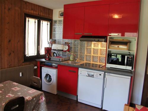 une cuisine avec des placards rouges et un lave-linge/sèche-linge dans l'établissement Appartement 3 pièces avec terrasse, parking, cheminée et vue montagne à La Clusaz - FR-1-459-54, à La Clusaz