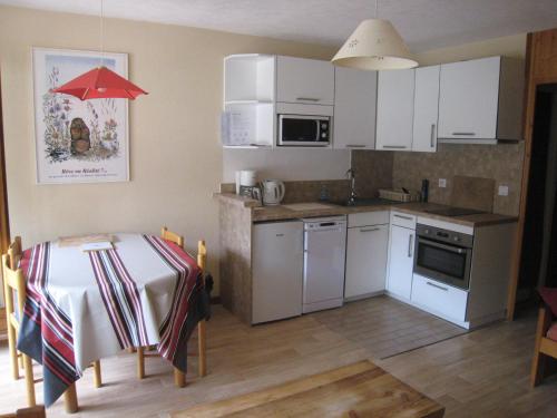 une cuisine avec des placards blancs et une table avec un parapluie rouge dans l'établissement Studio cabine au centre, balcon sud, parking, proche pistes et commerces - FR-1-459-89, à La Clusaz