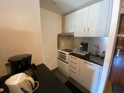 une petite cuisine avec des armoires blanches et un évier dans l'établissement 2 Pièces au Centre avec Cuisine Equipée et Balcon – La Clusaz - FR-1-459-116, à La Clusaz