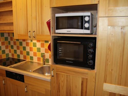 une cuisine avec un micro-ondes et un évier dans l'établissement Appartement 2 Pièces Rénové avec Balcon et Garage au Cœur de La Clusaz - FR-1-459-74, à La Clusaz