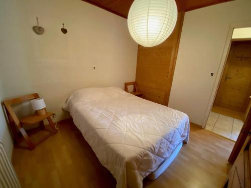 une chambre avec un lit, une lampe et une chaise dans l'établissement Appartement de 3 pièces avec balcon, cheminée et Wifi à La Clusaz - FR-1-459-99, à La Clusaz