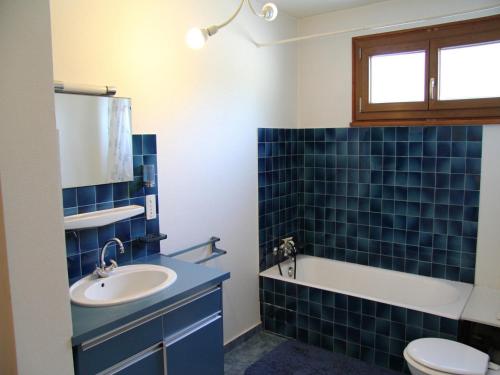 La salle de bains est pourvue de carrelage bleu, d'un lavabo et de toilettes. dans l'établissement Appartement de 3 pièces avec balcon, cheminée et Wifi à La Clusaz - FR-1-459-99, à La Clusaz