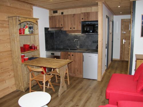 cocina con mesa de madera y sofá rojo en Studio rénové au cœur de La Clusaz, proche pistes et commerces - FR-1-459-115, en La Clusaz