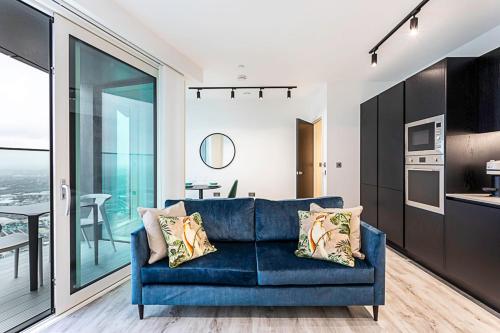 a living room with a blue couch and a kitchen at Icon Tower Flat VII in London