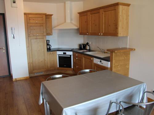 une cuisine avec des armoires en bois et une table et des chaises dans l'établissement Charmant appartement au centre du village, proche des stations de ski - 4 personnes - FR-1-459-163, à Saint-Jean-de-Sixt
