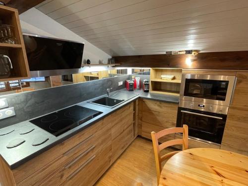 Il comprend une cuisine équipée d'une cuisinière, d'un évier et d'une table. dans l'établissement Appartement Mansardé 3 Pièces 74m², Balcon Sud, Parking Privé, Wifi - FR-1-459-183, à La Clusaz